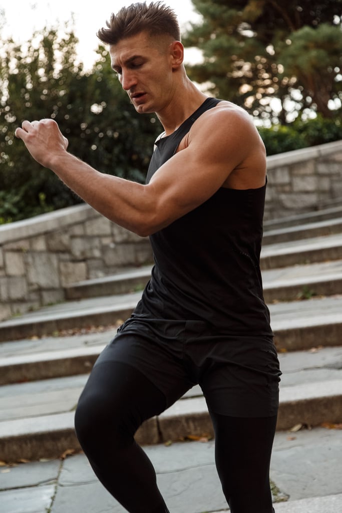 Coach in a black sleeveless top is working out outdoors.